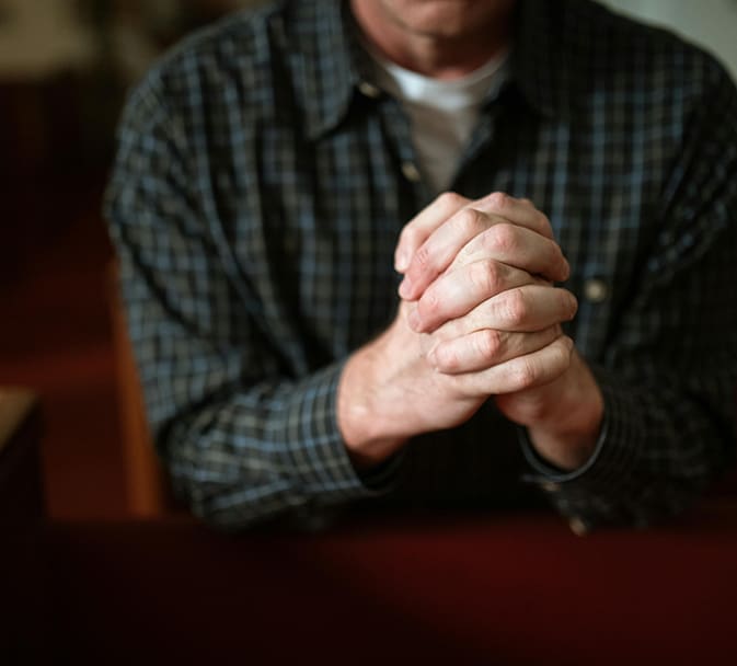 A man sitting at a table with his hands clasped together.