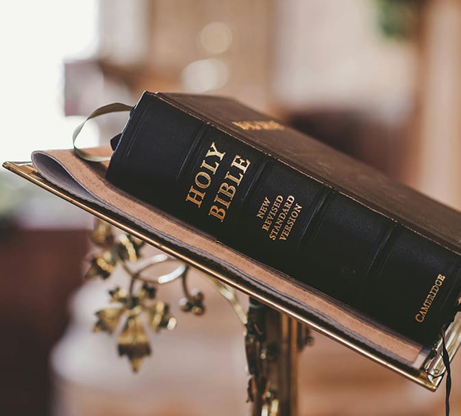 A bible is sitting on top of a book.