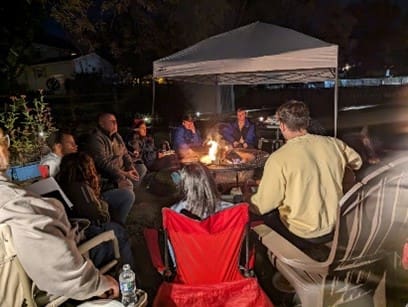 A group of people sitting around a fire pit.