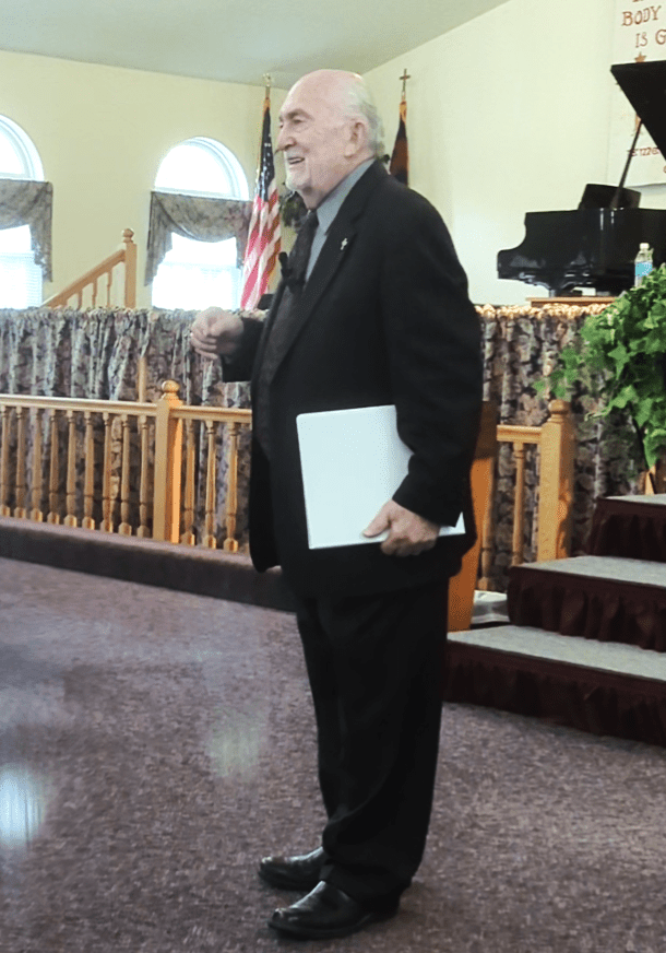 A man in suit holding papers and standing on stairs.