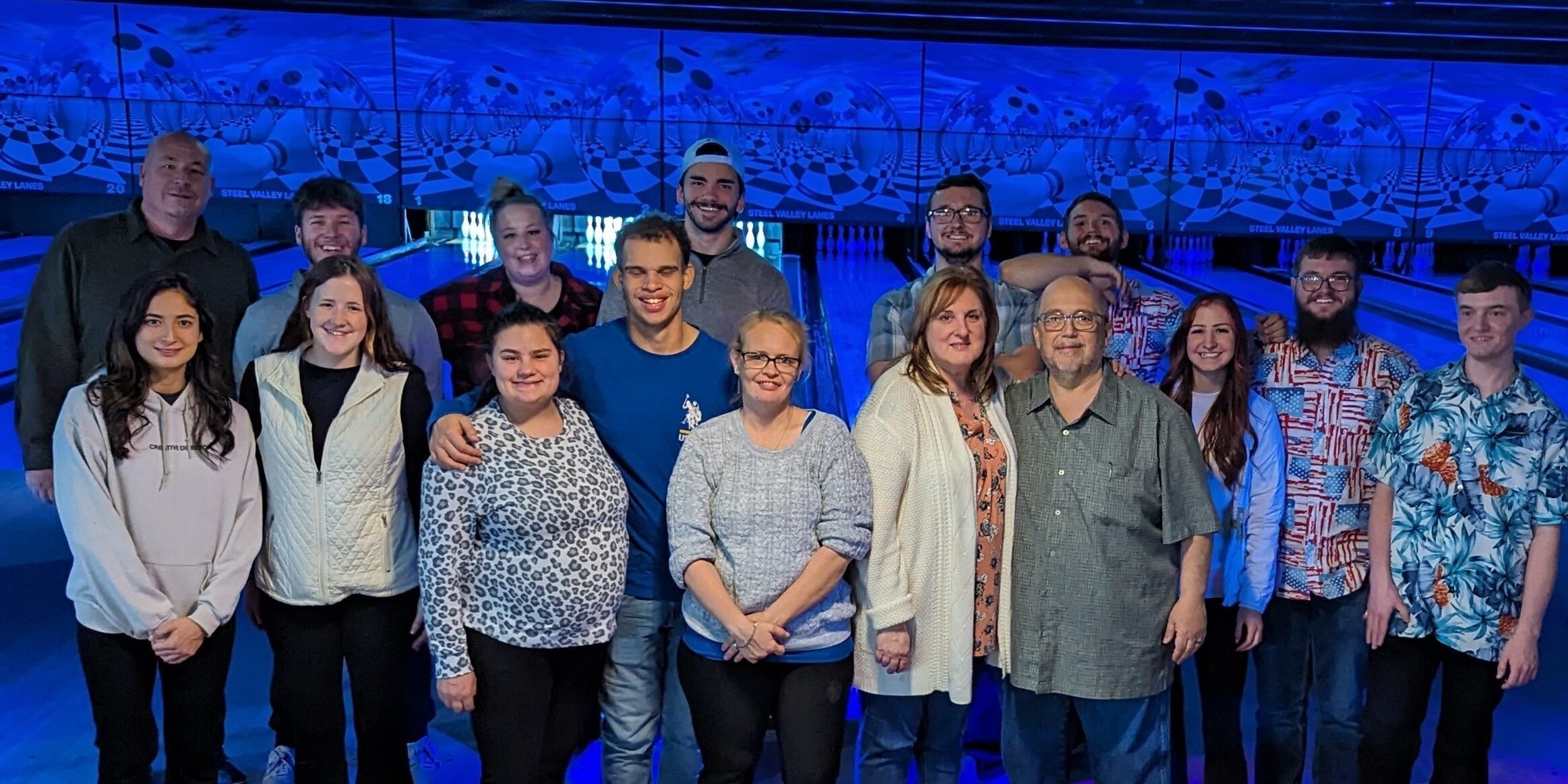 A group of people standing in front of a blue wall.